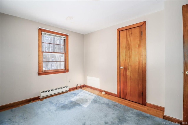 spare room featuring wood-type flooring and a baseboard heating unit