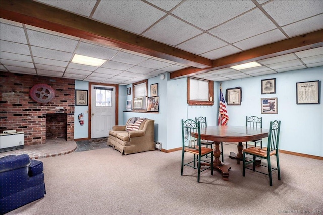 carpeted dining area featuring a fireplace and a paneled ceiling