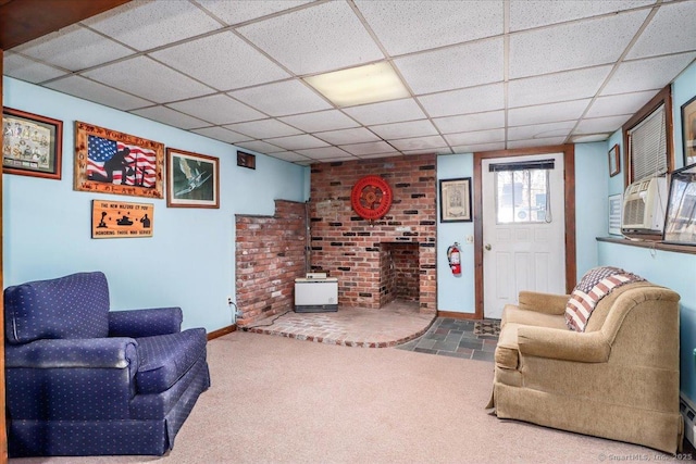 carpeted living room with cooling unit, a drop ceiling, and a wood stove