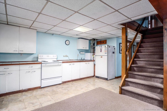 kitchen with a paneled ceiling, white cabinets, and white appliances