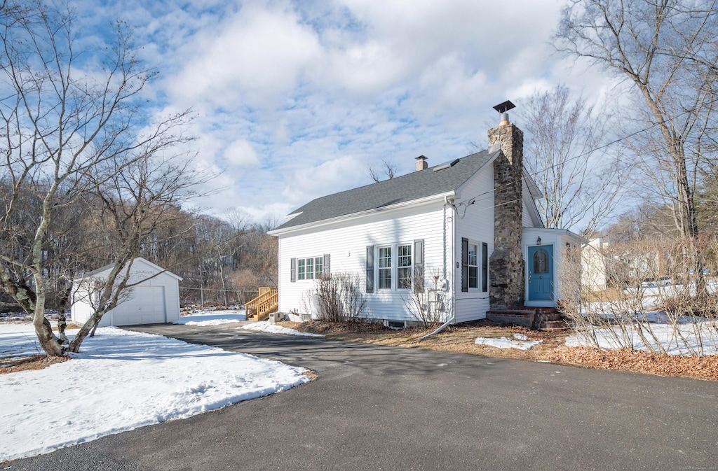 view of snowy exterior with a garage and an outbuilding