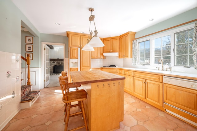 kitchen with decorative light fixtures, butcher block counters, sink, a center island, and light tile patterned floors