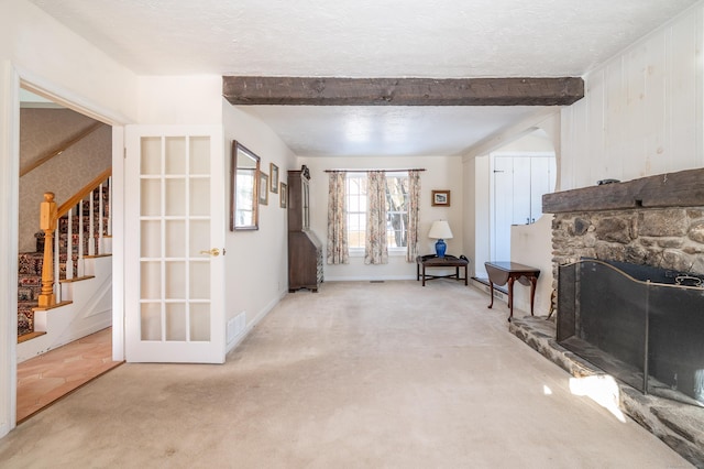 carpeted living room featuring a textured ceiling, a fireplace, and beamed ceiling