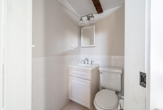 bathroom featuring tile patterned floors, toilet, a textured ceiling, tile walls, and vanity