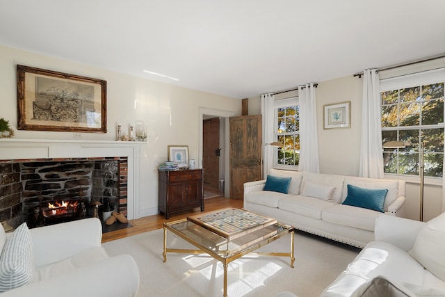 living room with wood finished floors, plenty of natural light, and a lit fireplace