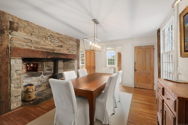 dining space with light wood-type flooring, a chandelier, and a wood stove