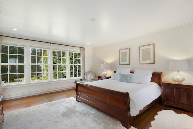 bedroom with wood finished floors and ornamental molding