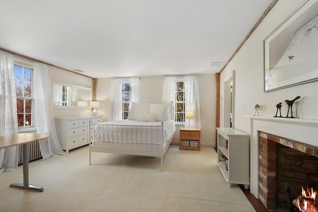bedroom featuring a brick fireplace and light colored carpet
