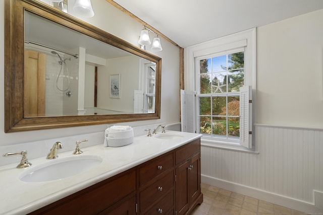 full bath with wainscoting, double vanity, and a shower