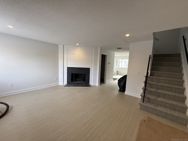 unfurnished living room with light hardwood / wood-style floors, a large fireplace, and a textured ceiling