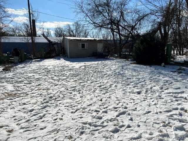 yard covered in snow featuring a shed