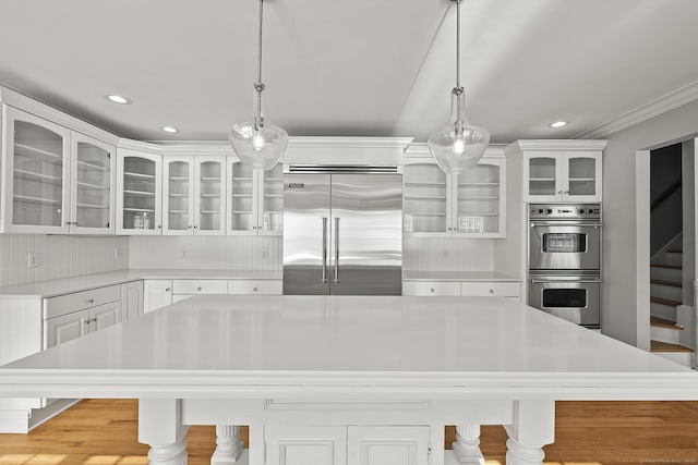 kitchen featuring white cabinetry, stainless steel appliances, a center island, a kitchen bar, and decorative light fixtures