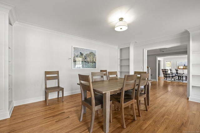 dining area featuring built in shelves, ornamental molding, and light hardwood / wood-style floors