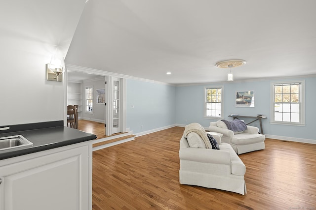 living room with ornamental molding, a healthy amount of sunlight, and light wood-type flooring