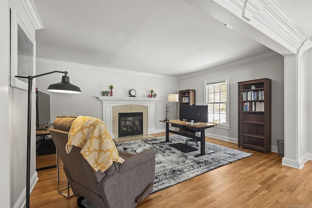 living room featuring a tiled fireplace, crown molding, and light hardwood / wood-style floors