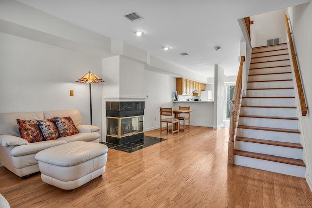 living room with a tiled fireplace and hardwood / wood-style floors