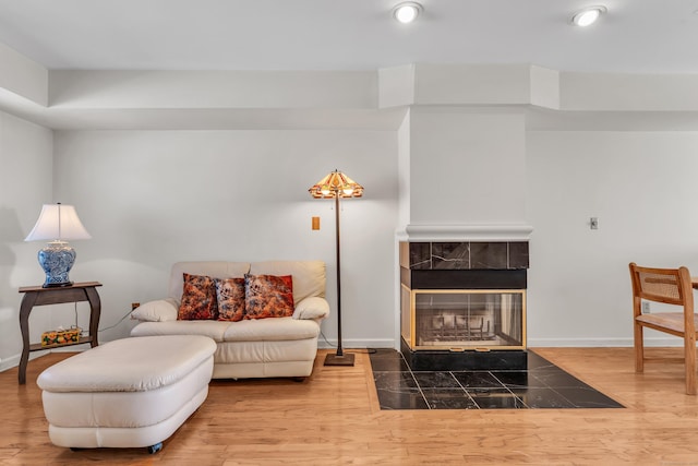 living room featuring a tiled fireplace and hardwood / wood-style floors