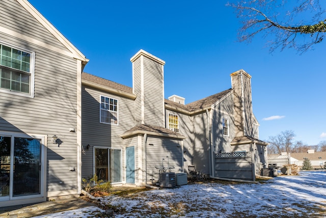 snow covered house featuring central air condition unit