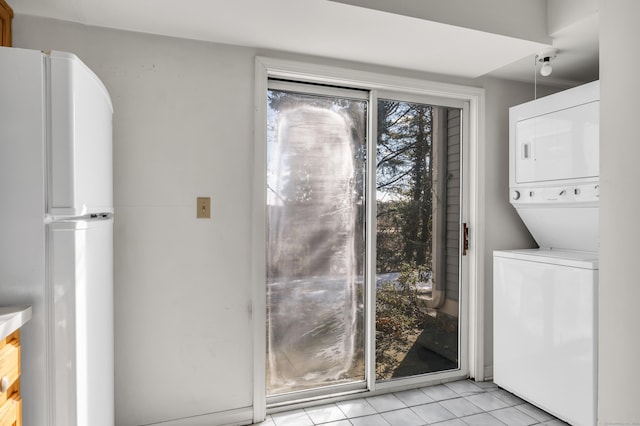 clothes washing area featuring light tile patterned floors and stacked washer / dryer