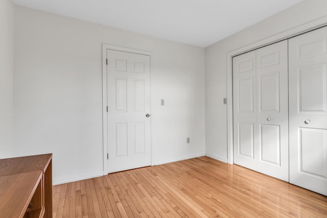 unfurnished bedroom featuring light hardwood / wood-style flooring and a closet