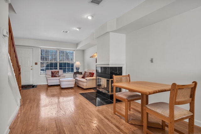 dining space featuring a tiled fireplace and wood-type flooring