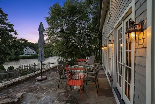 patio terrace at dusk with a water view and french doors