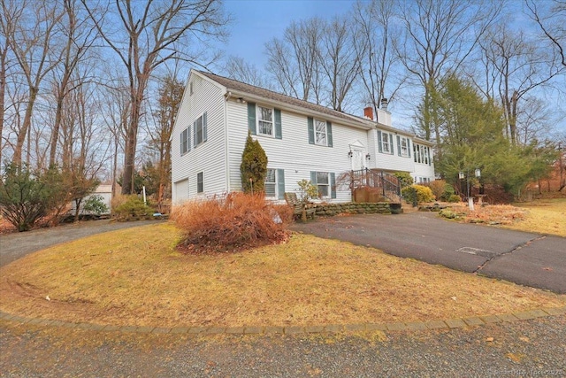 bi-level home with driveway, a chimney, and an attached garage