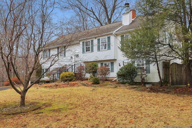 split foyer home with a front yard, fence, and a chimney