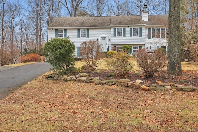 raised ranch with aphalt driveway and a chimney