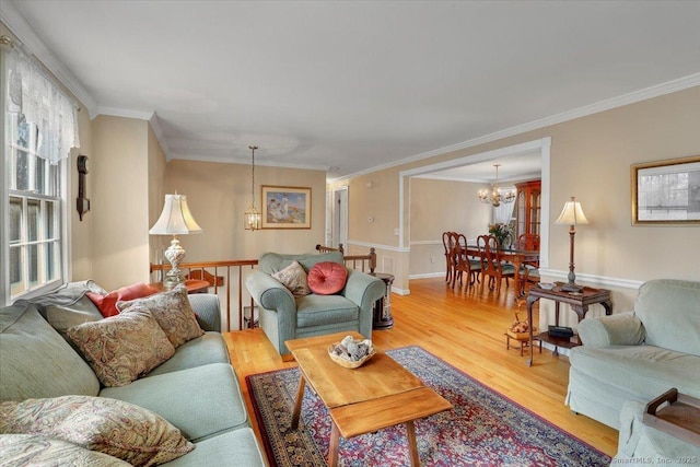 living room featuring crown molding, wood finished floors, a wealth of natural light, and a notable chandelier