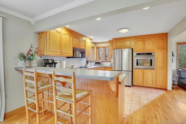 kitchen featuring appliances with stainless steel finishes, ornamental molding, a peninsula, and light wood finished floors