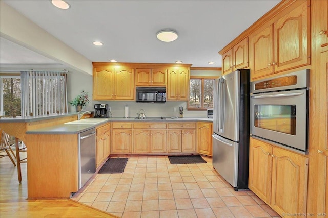 kitchen featuring recessed lighting, a peninsula, a breakfast bar, a sink, and appliances with stainless steel finishes