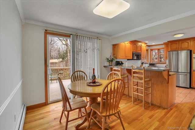 dining room with light wood finished floors, baseboards, ornamental molding, and baseboard heating