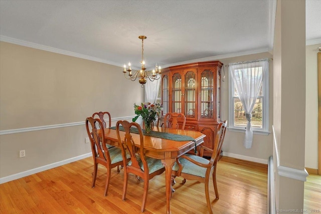 dining space featuring light wood-type flooring, an inviting chandelier, baseboards, and crown molding