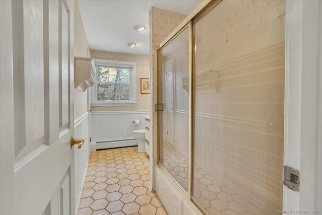 full bathroom featuring a baseboard radiator, toilet, wainscoting, a shower stall, and wallpapered walls