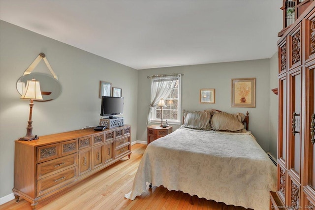 bedroom featuring light wood-style floors, a baseboard radiator, and baseboards