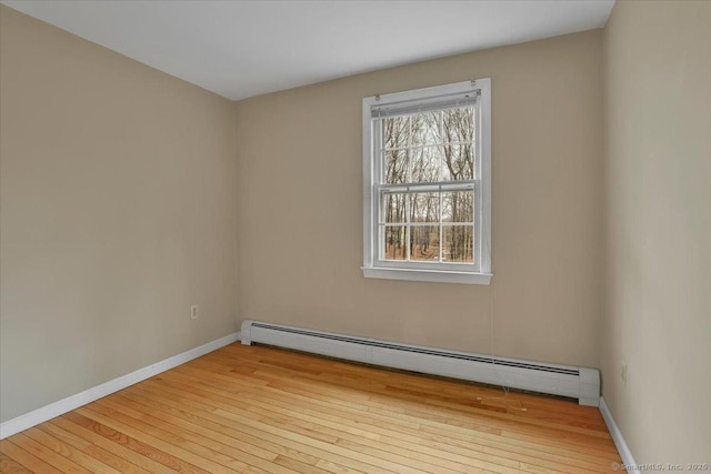 spare room featuring hardwood / wood-style flooring, baseboards, and a baseboard heating unit