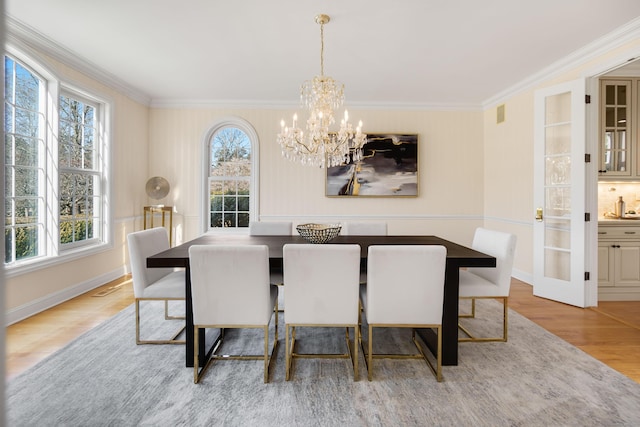 dining space with crown molding, light hardwood / wood-style flooring, and a chandelier