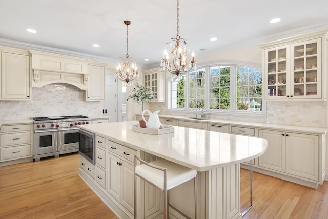 kitchen featuring a kitchen bar, a center island, black microwave, cream cabinets, and range with two ovens