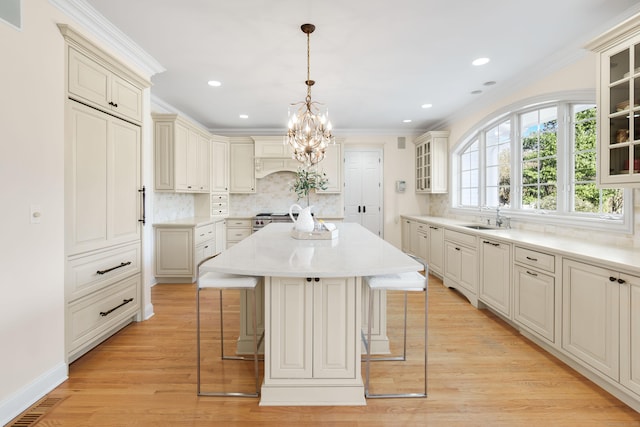 kitchen with pendant lighting, sink, crown molding, a breakfast bar, and a kitchen island