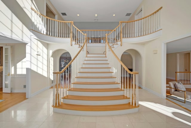 stairway with tile patterned flooring and a high ceiling