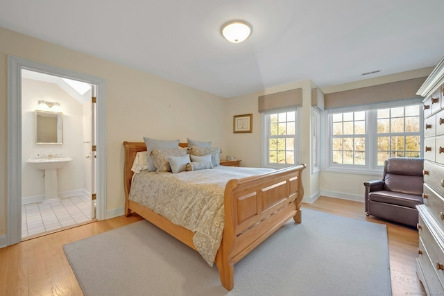 bedroom with light hardwood / wood-style flooring and ensuite bathroom