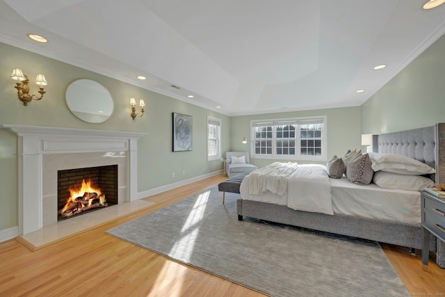 bedroom featuring a raised ceiling, ornamental molding, and light hardwood / wood-style flooring