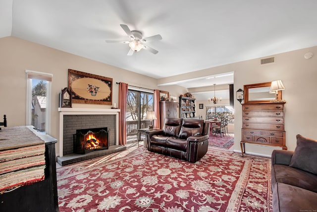 living room with vaulted ceiling, plenty of natural light, ceiling fan with notable chandelier, and a fireplace