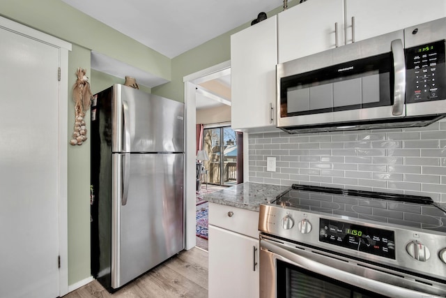 kitchen featuring light stone countertops, white cabinetry, appliances with stainless steel finishes, and decorative backsplash