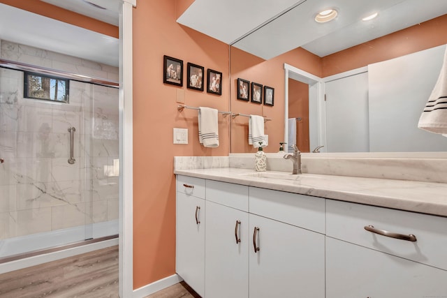 bathroom with vanity, a shower with shower door, and wood-type flooring