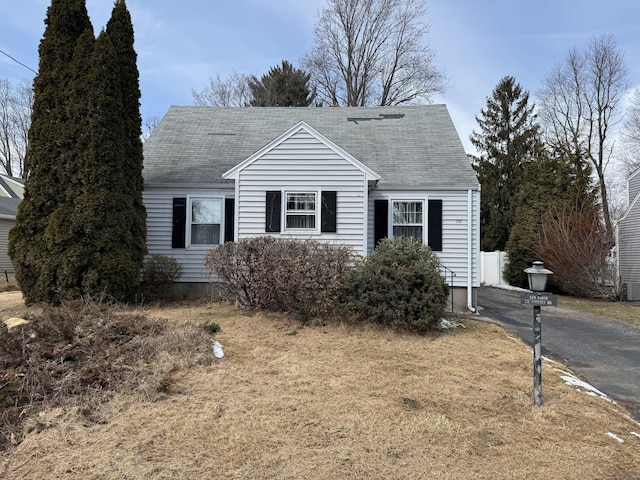 cape cod home featuring aphalt driveway and roof with shingles