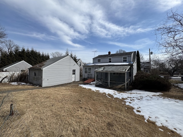 snow covered back of property featuring an outbuilding, a lawn, and a chimney