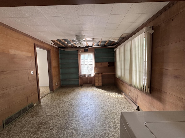 unfurnished room featuring a ceiling fan, visible vents, and wooden walls