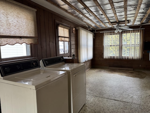 clothes washing area with laundry area, separate washer and dryer, a wealth of natural light, and wooden walls